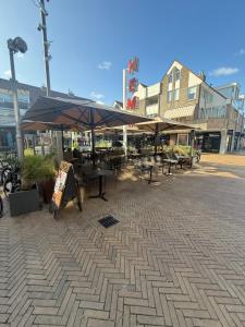 a patio with tables and umbrellas on a city street at Beach Hotel Katwijk in Katwijk