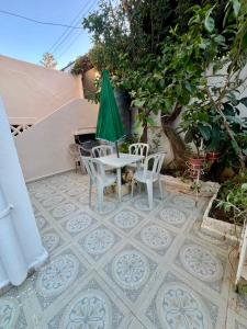 Ein Tisch und Stühle mit einem grünen Sonnenschirm auf einer Terrasse in der Unterkunft Ariam in Annaba