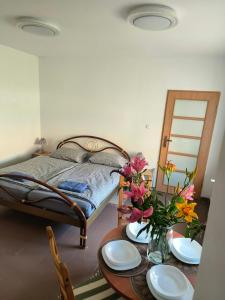 a bedroom with a bed and a table with plates and flowers at Apartament przy weneckim mostku in Kowary