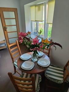a dining room table with plates and flowers on it at Apartament przy weneckim mostku in Kowary
