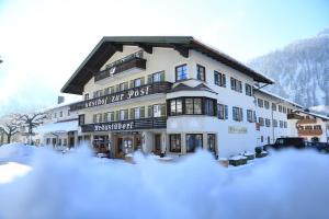 een groot gebouw met sneeuw ervoor bij Klosterhof zur Post in Bayrischzell