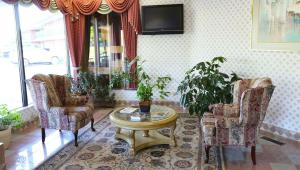 a living room with chairs and a table and a tv at Magnuson Hotel Howell/Brighton in Howell +8 photos