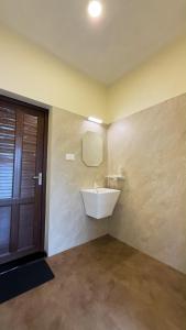 a bathroom with a white sink and a door at Kadapu stay in Udiyāvara