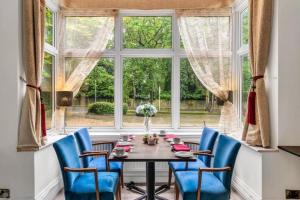 a table with blue chairs in a room with a window at Seka Inn Hotel in Crowthorne