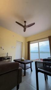 a living room with a couch and a ceiling fan at Kadapu stay in Udiyāvara