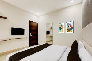 a white bedroom with a bed and a television at Townhouse Hotel Sec- 54 Golf Course Road in Gurgaon