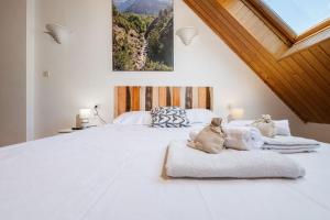 a large white bed with two cats laying on it at Apto Aloha Panticosa | Piscina | WIFI | Vistas in Panticosa +21 photos