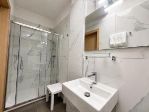a white bathroom with a sink and a shower at Hotel International in Tarvisio