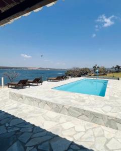a swimming pool with benches next to the water at Brisa do Lago Pousada in Capitólio