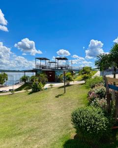 a building on the shore of the water with a park at Brisa do Lago Pousada in Capitólio