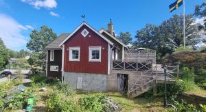 a red and black house with a porch at The Red Mini Cottage in Huddinge