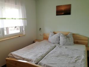 a bedroom with a bed with white sheets and a window at Bungalow Schwielochsee in Schwielochsee