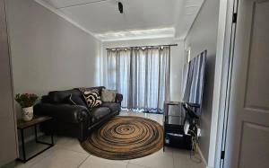 a living room with a leather couch and a large rug at R&R at Summerview Sonstraal Heights in Windsor Park