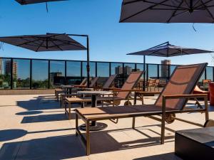 a row of chairs and tables with umbrellas on a roof at Novotel Uberlândia in Uberlândia