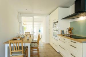 a kitchen with white cabinets and a table and chairs at Villa Trafal - Proche plage in Saint-Michel-en-lʼHerm