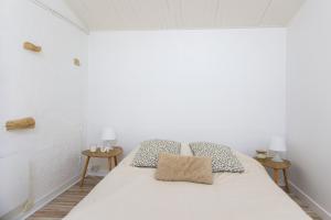 a bedroom with a white bed with two tables at Villa Trafal - Proche plage in Saint-Michel-en-lʼHerm