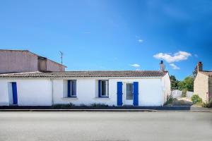 a white house with blue shutters on a street at Villa Trafal - Proche plage in Saint-Michel-en-lʼHerm