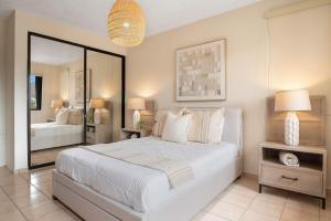a bedroom with a large white bed and a mirror at Boho 2BR Retreat - Ocean View Terrace & Pool in Buena Vista