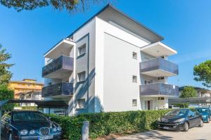 een wit gebouw met auto's ervoor geparkeerd bij Residence Ca'Tullio in Bibione