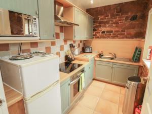 a small kitchen with blue cabinets and a white refrigerator at The Coach House in Wigton +12 photos