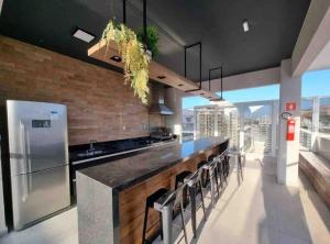 a kitchen with a long counter with stools at Studio Luxo Completo Independência 915- São Mateus in Juiz de Fora +25 photos