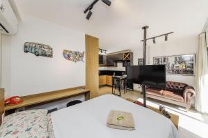a room with a bed and a tv and a kitchen at Studio Luxo Completo Independência 915- São Mateus in Juiz de Fora