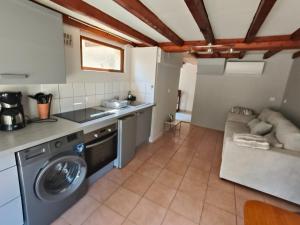 a kitchen with a washing machine and a couch at Gîte - La Gariotte du Causse in Frayssinet