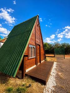a small wooden house with a green roof at Chalé da Chapada in Chapada dos Guimarães