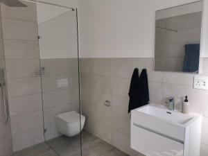a bathroom with a toilet and a glass shower at Sunset Dunes in Cape Town
