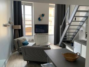 a living room with a staircase and a television at La loge des Salinières in Bordeaux