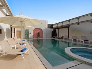 a pool with chairs and an umbrella next to a building at Mercure Abu Dhabi Downtown in Abu Dhabi