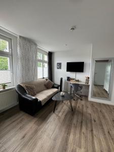 a living room with a black couch and a mirror at WOHNEN AM SCHLOSSPARK - Bad Salzuflen - nahe Messe, schnelles WLAN, freie Parkplätze, Frühstück verfügbar in Bad Salzuflen