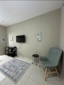 a living room with a chair and a flat screen tv at Cosy Studio - Desert Breeze in Ghantoot