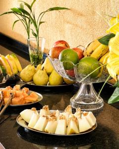 a table topped with plates of fruit and vegetables at Brisa do Lago Pousada in Capitólio