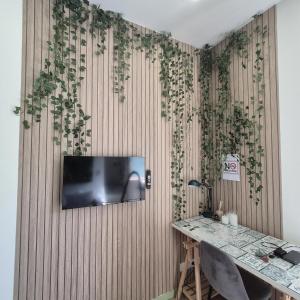 a room with a tv on a wooden wall with plants at Appartement Jungle 4 places in Saint-Étienne