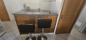 a kitchen with a sink and two bar stools at Les Gites D'Angres in Angres