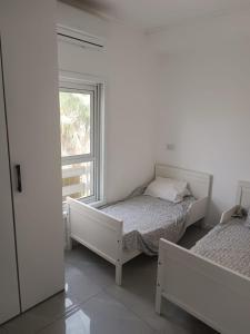 a bedroom with two beds and a window at Dizengoff 20 in Netanya