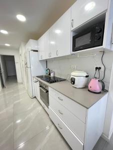 a kitchen with white cabinets and a pink appliance at Dizengoff 20 in Netanya +5 photos