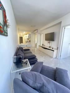 a living room with two blue couches and a television at Dizengoff 20 in Netanya