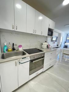 a white kitchen with a sink and a stove at Dizengoff 20 in Netanya