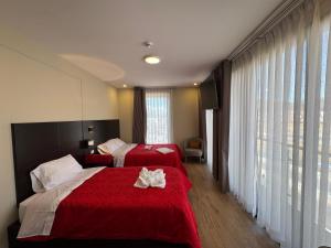 two beds in a hotel room with red sheets at Hotel San Miguel Cusco in Cusco