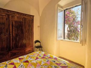 a bedroom with a quilt on a bed and a window at Apartment Risorgimento Apartment by Interhome in Cipressa
