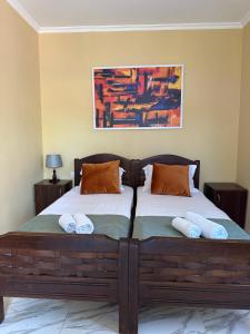 a bedroom with two beds with pillows and a painting at Cottage Shara - შარა in Ureki
