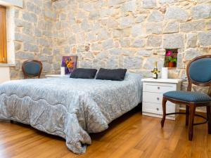 a bedroom with a bed and a stone wall at Villa S'Olioni by Interhome in Loceri