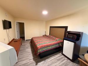 a bedroom with a bed and a flat screen tv at Golden Knight Motel in Gresham