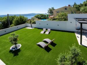 a yard with green grass and two chairs and a table at Villa Black Imperium by Interhome in Mošćenička Draga