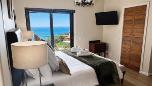 a bedroom with a bed with a view of the ocean at Aqua Terra Boutique Guesthouse - Simon's Town, Cape Town in Simonʼs Town