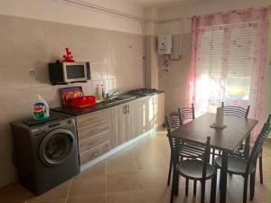 a kitchen with a washing machine and a table with chairs at Aparts 3 F3 BEJAIA VACANCE in Bejaïa