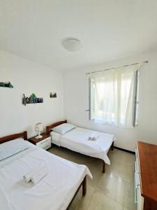 two beds in a white room with a window at Apartments Marino in Supetar