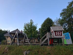 a playground with a play structure and a house at Zavetišče v Gozdu in Križe